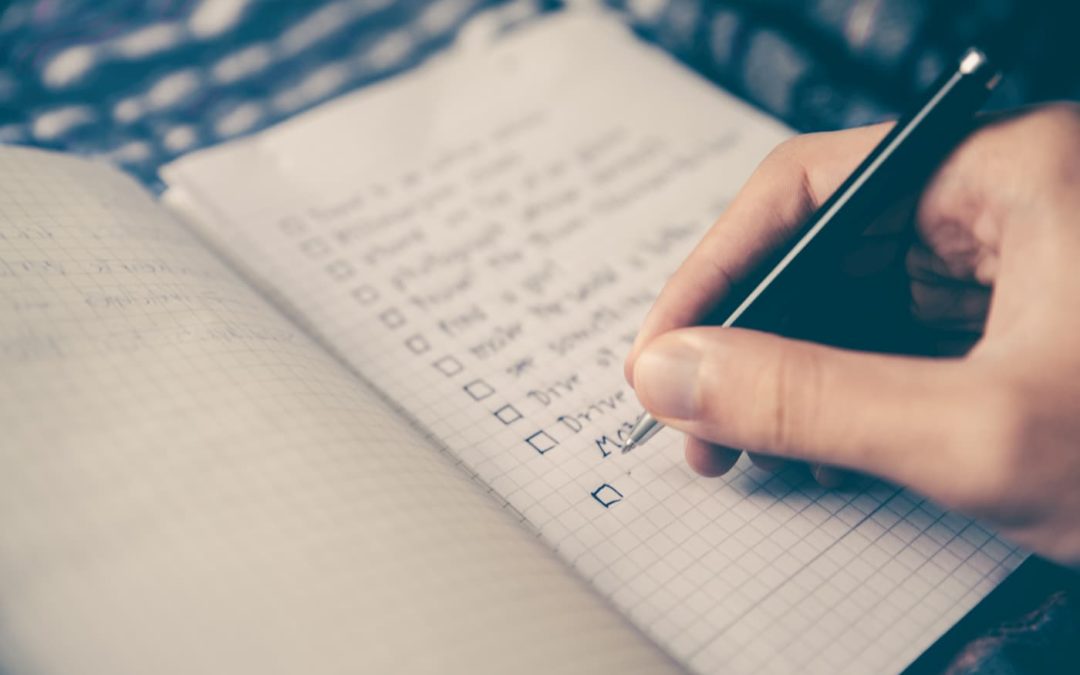 A person writing a checklist in a notebook