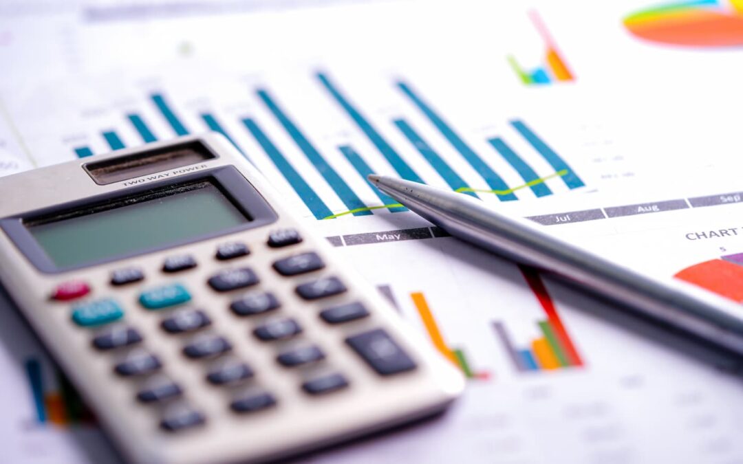 an image of a calculator sitting atop financial management bar graphs