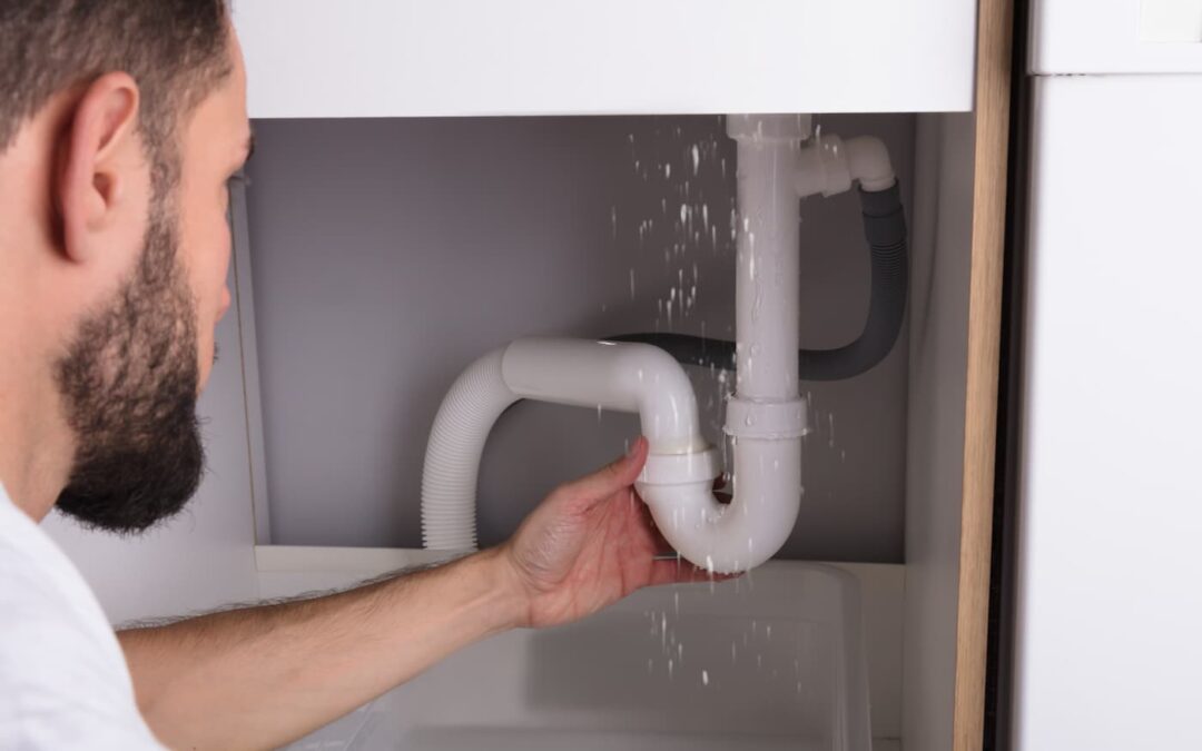 a man assessing a water leak underneath a sink.