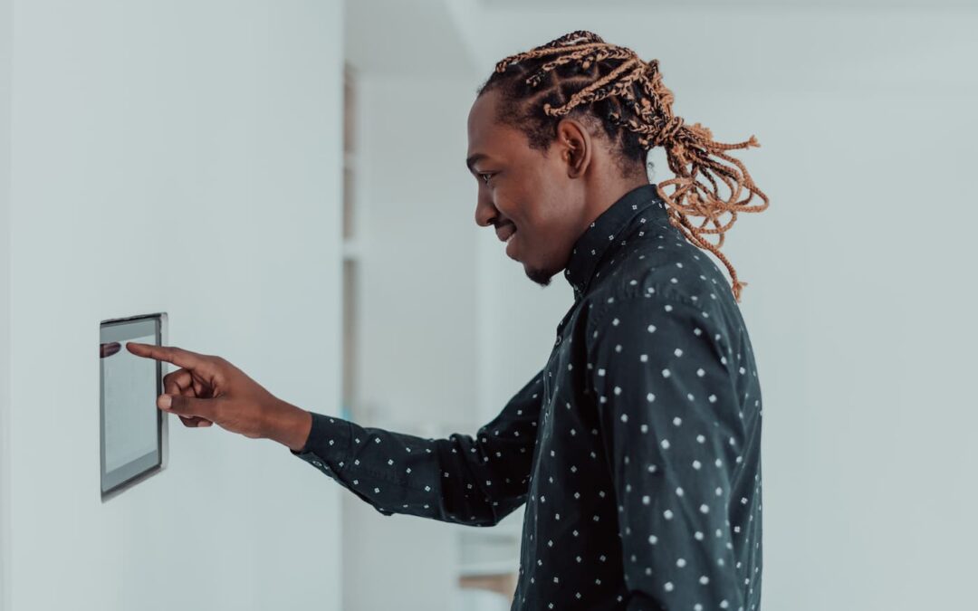 A man with long braids punches a code into his wall-mounted rental property security system