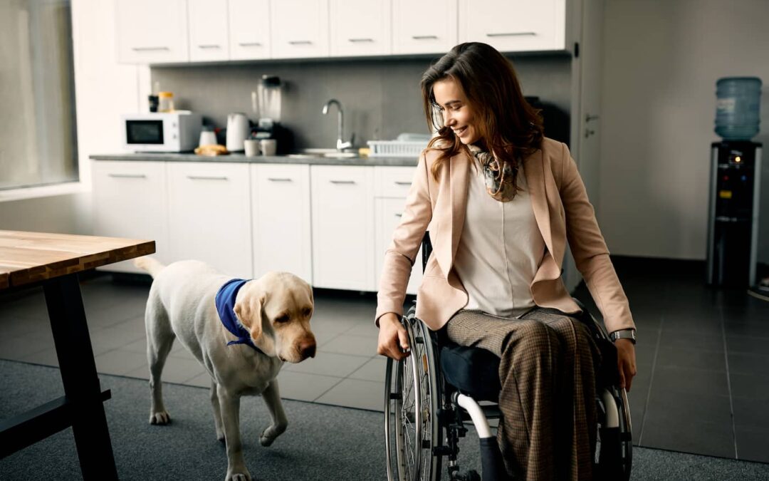 A women in a wheelchair and her yellow service dog navigate her kitchen designed for accessibility.